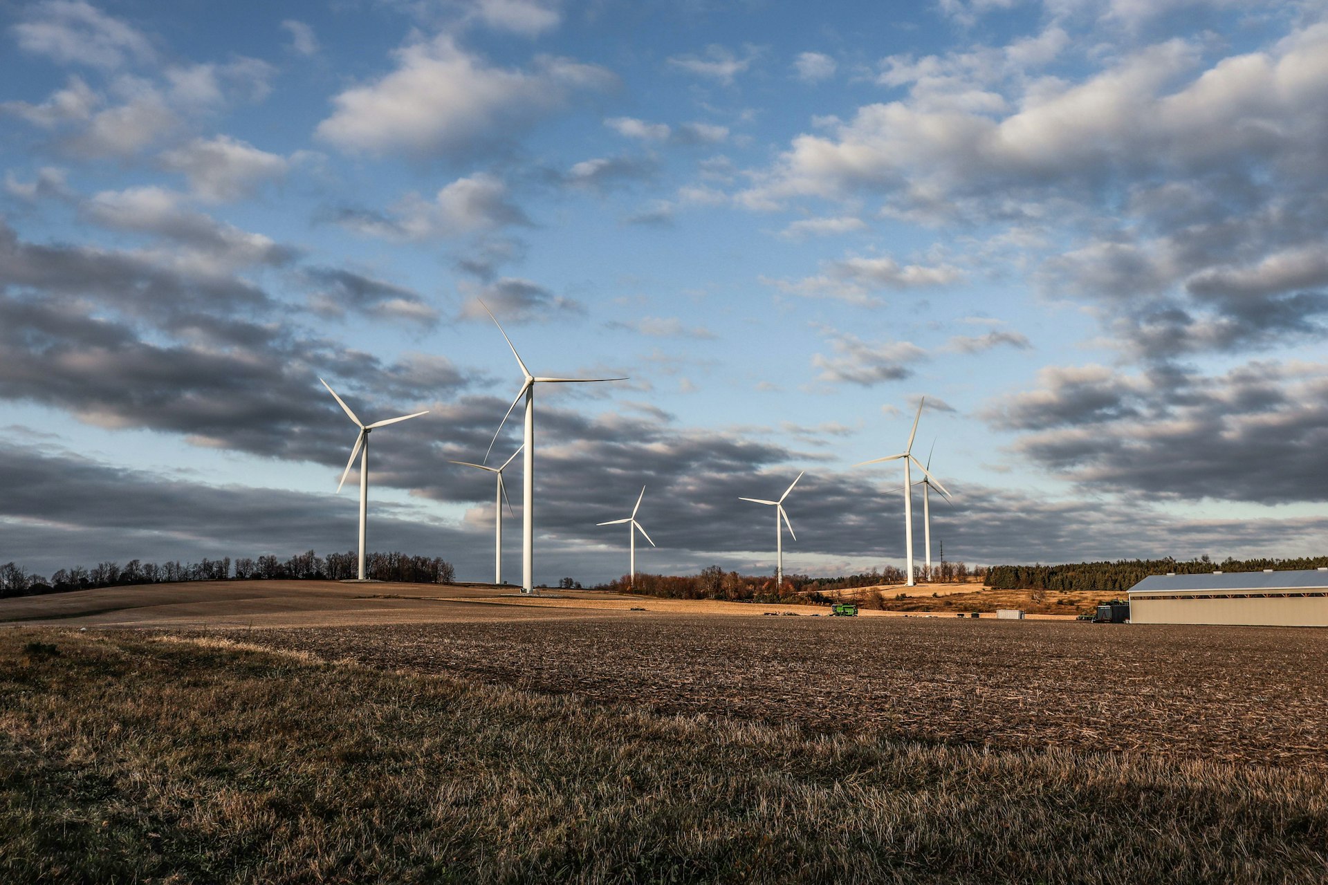 white wind turbines on brown grass field under white clouds and blue sky during daytime